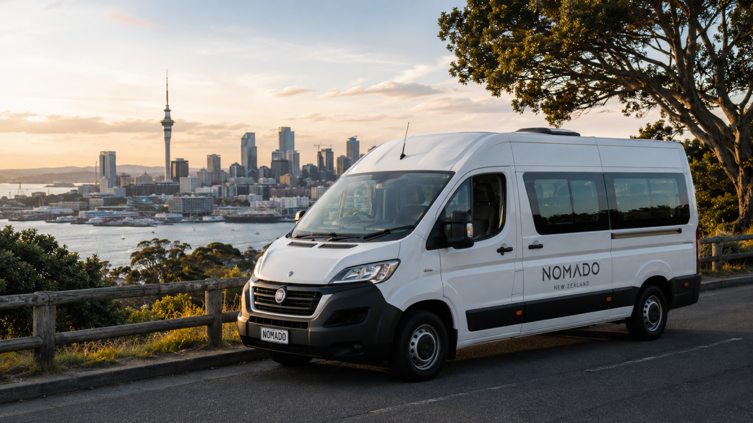 Nomado campervan overlooking Auckland skyline at sunset for campervan rental Auckland road trips and New Zealand travel.